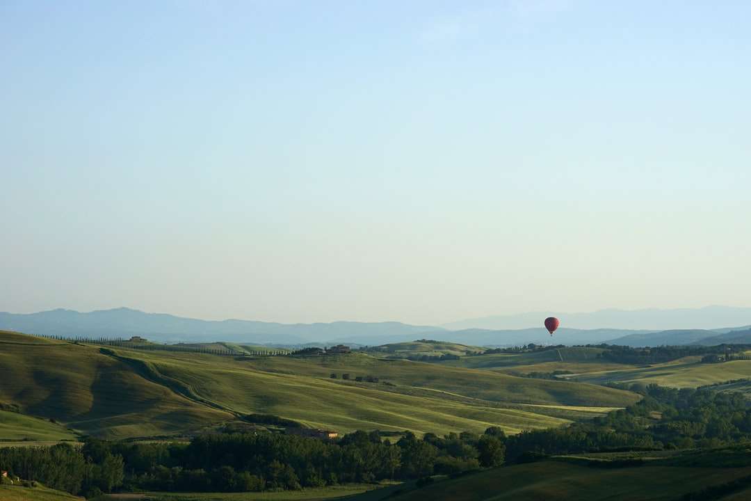 červený horkovzdušný balón letící nad zelené louky skládačky online