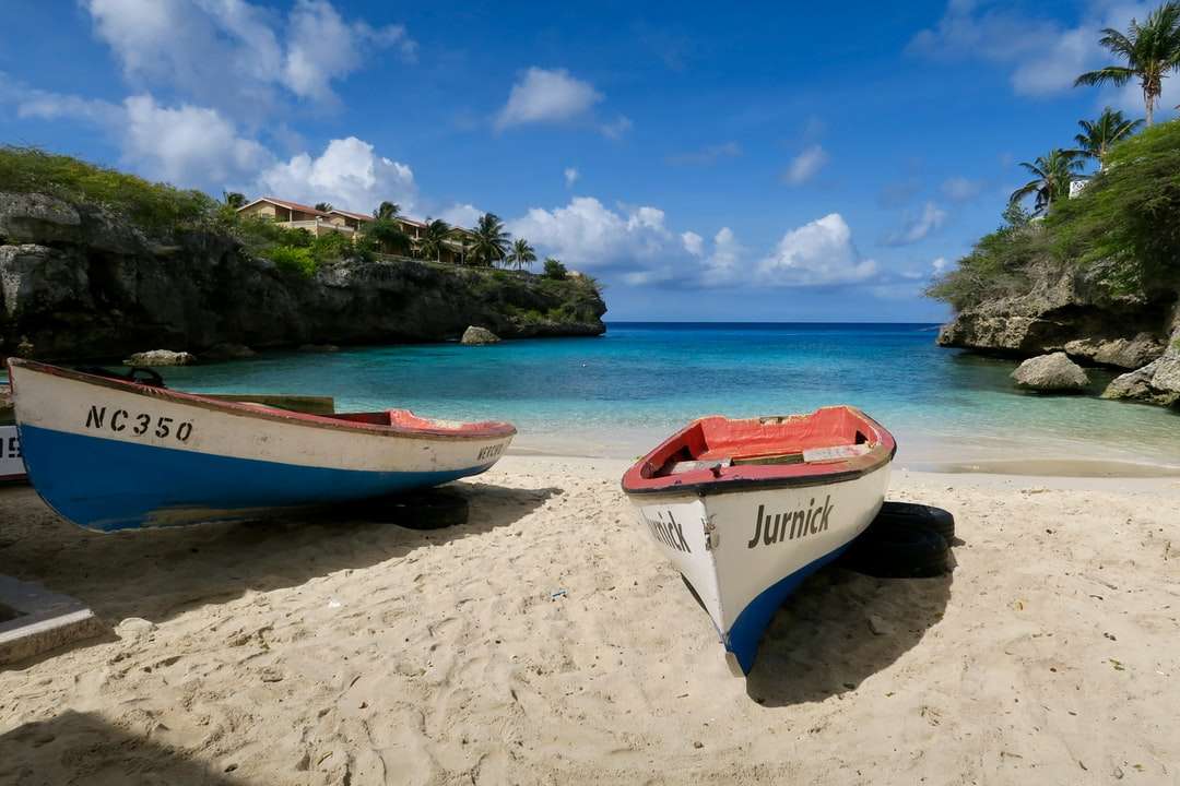 röd och vit båt på stranden under dagtid pussel på nätet