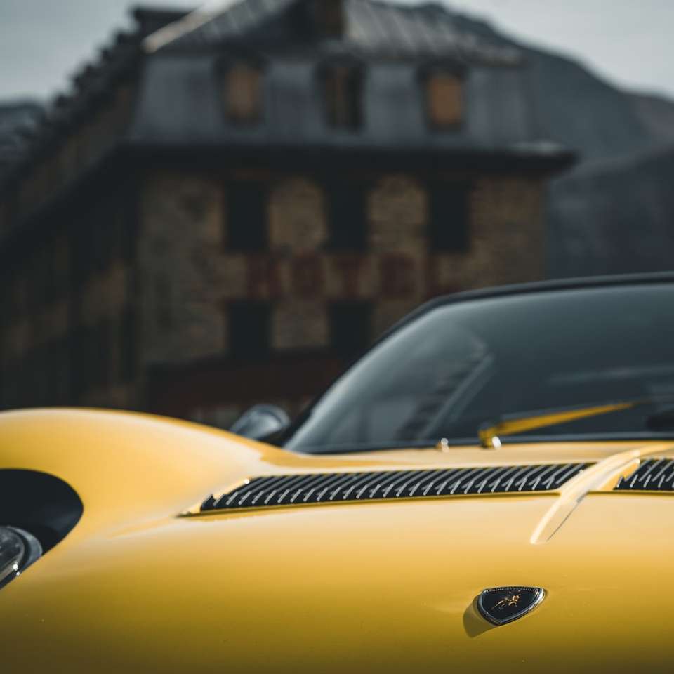 Yellow Porsche 911 estacionado perto de prédio de concreto marrom quebra-cabeças online