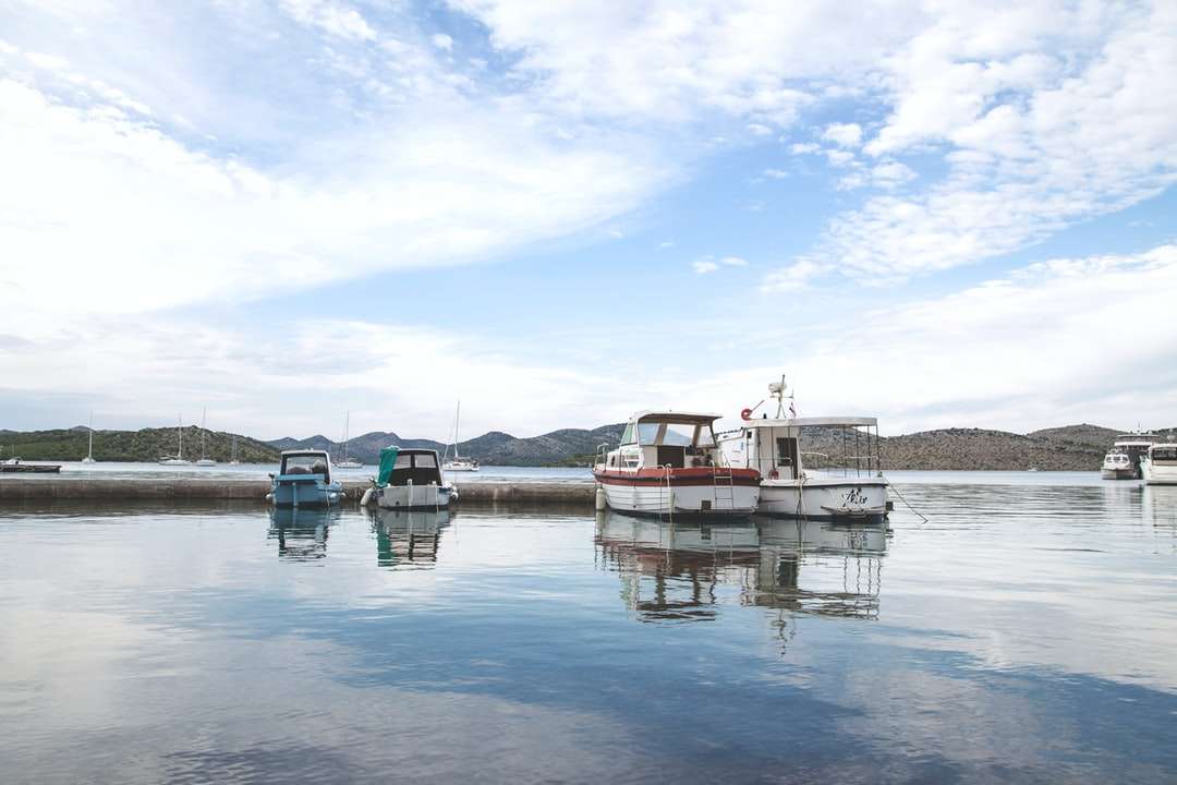 barca albă și roșie pe apă sub cerul albastru în timpul zilei puzzle online