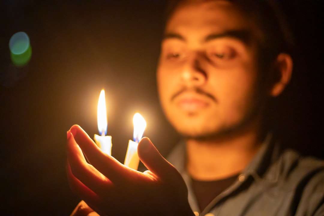 man in gray shirt holding lighted candle online puzzle