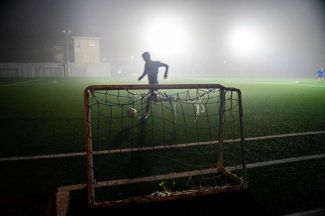 homem de camisa preta em pé na rede do gol de futebol quebra-cabeças online