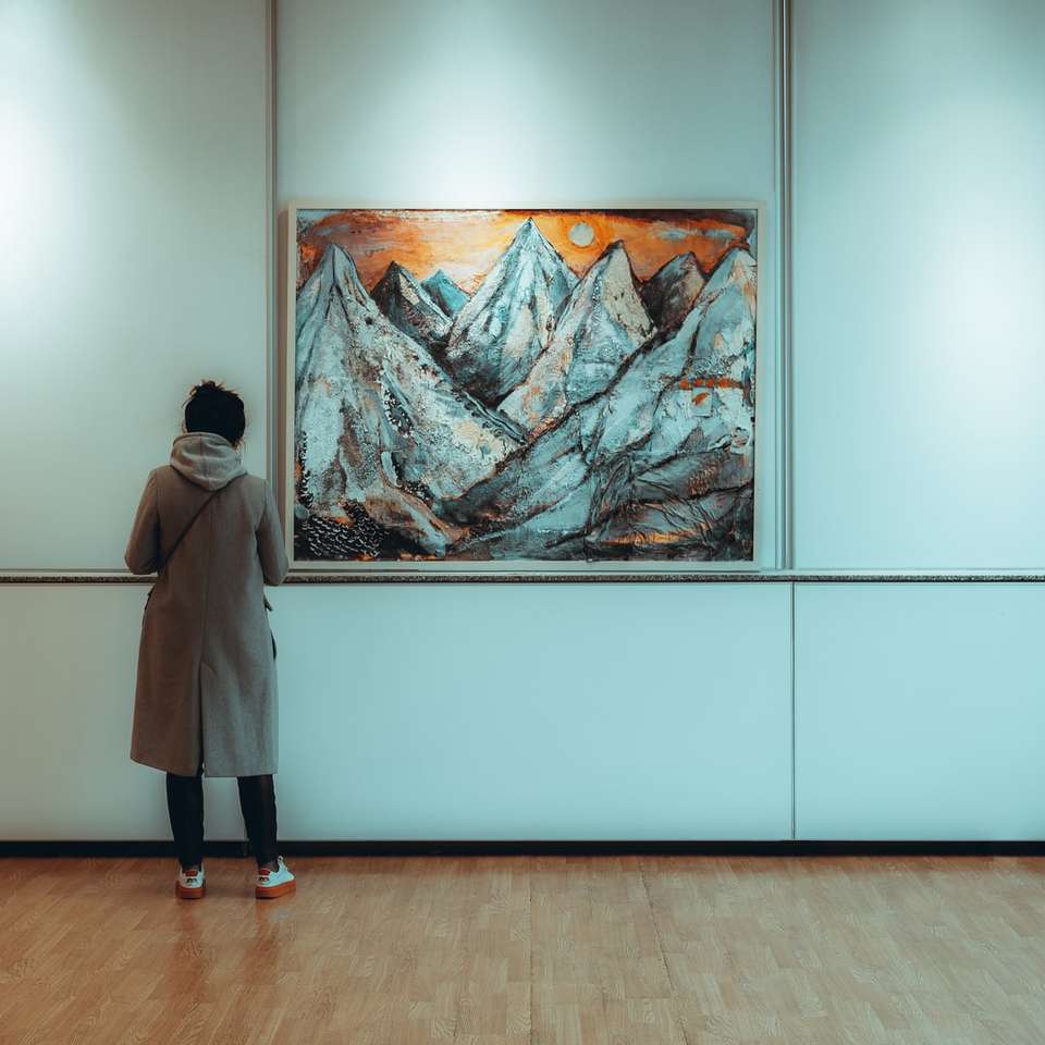 femme en manteau gris debout près de la peinture puzzle en ligne