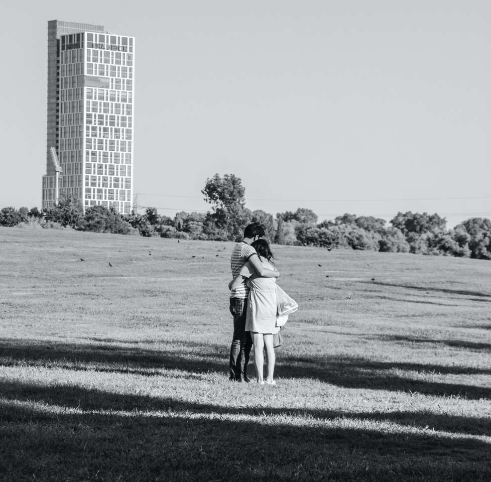 fotografie în tonuri de gri a bărbatului și a femeii care merg pe câmpul de iarbă puzzle online
