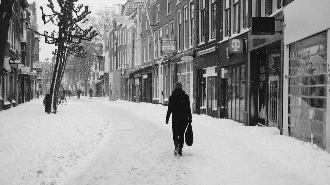 person i svart kappa som går på snötäckt väg pussel på nätet