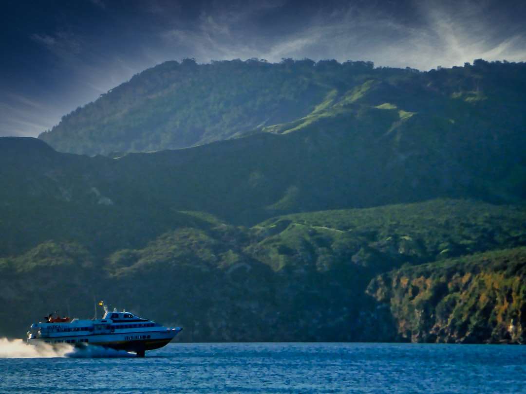 Barco blanco y negro en el mar cerca de la montaña durante el día rompecabezas en línea