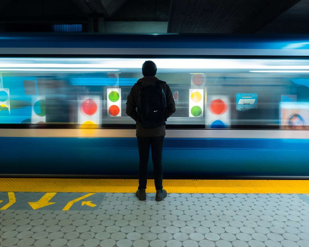 άντρας σε μαύρο σακάκι στέκεται στο σιδηροδρομικό σταθμό online παζλ