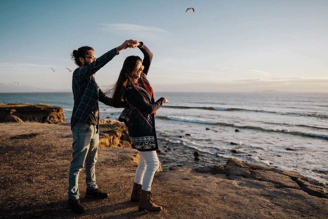 muž a žena stojící na pláži během dne skládačky online