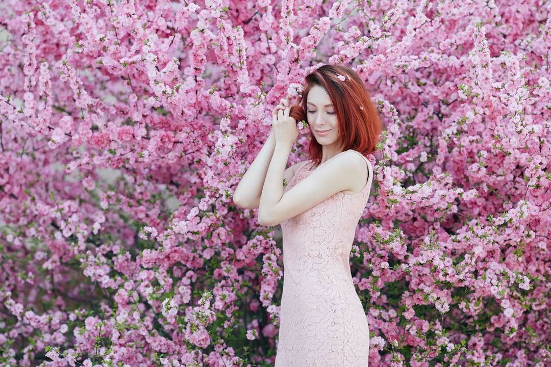 ピンクの花の横に立っている白いノースリーブのドレスの女性 オンラインパズル