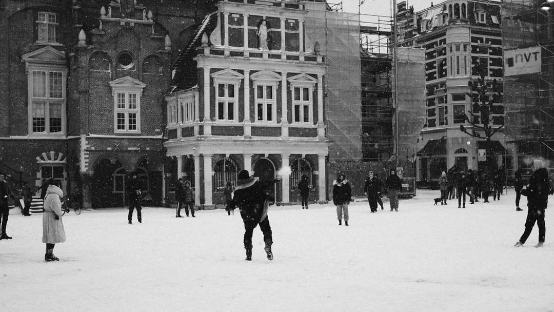 pessoas caminhando em um campo coberto de neve perto do prédio quebra-cabeças online