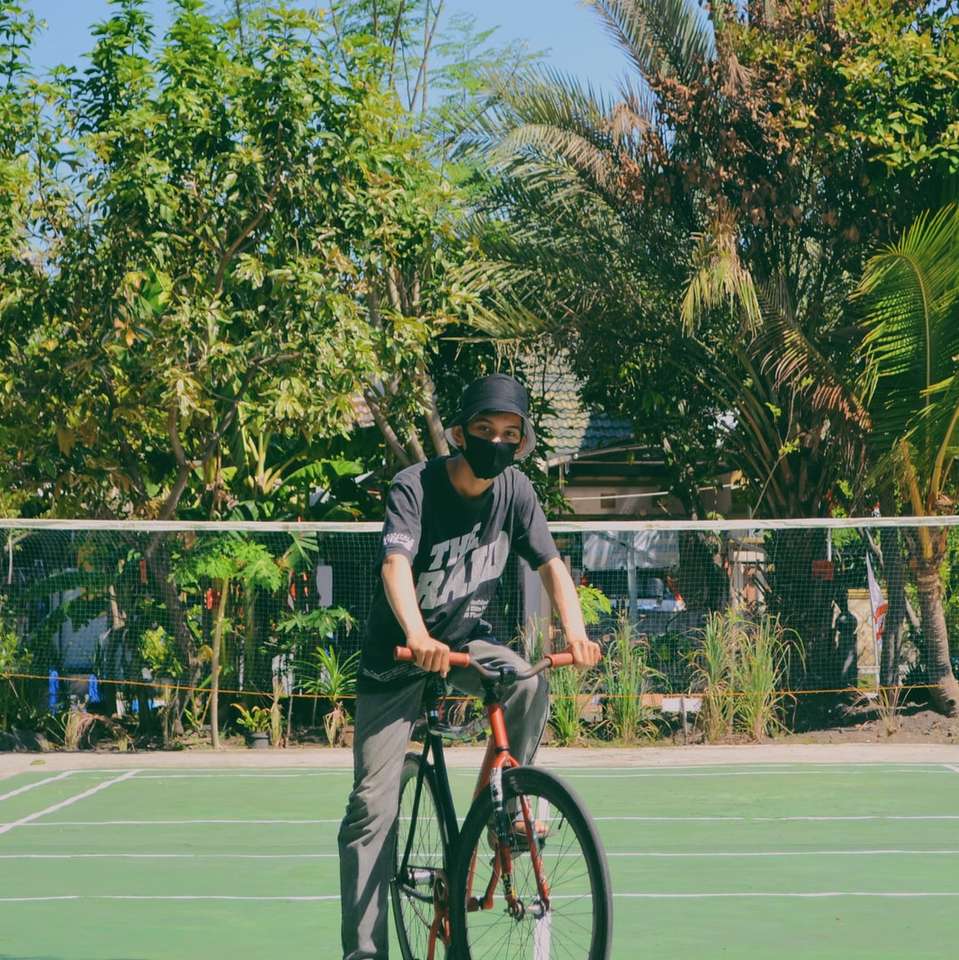 Mann im schwarzen Helm, der Fahrrad auf Schienenfeld reitet Puzzlespiel online