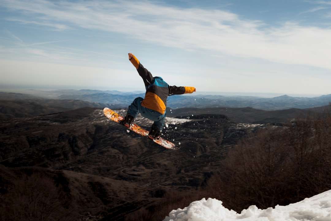 homem de jaqueta azul e calça preta fazendo esqui na neve puzzle online