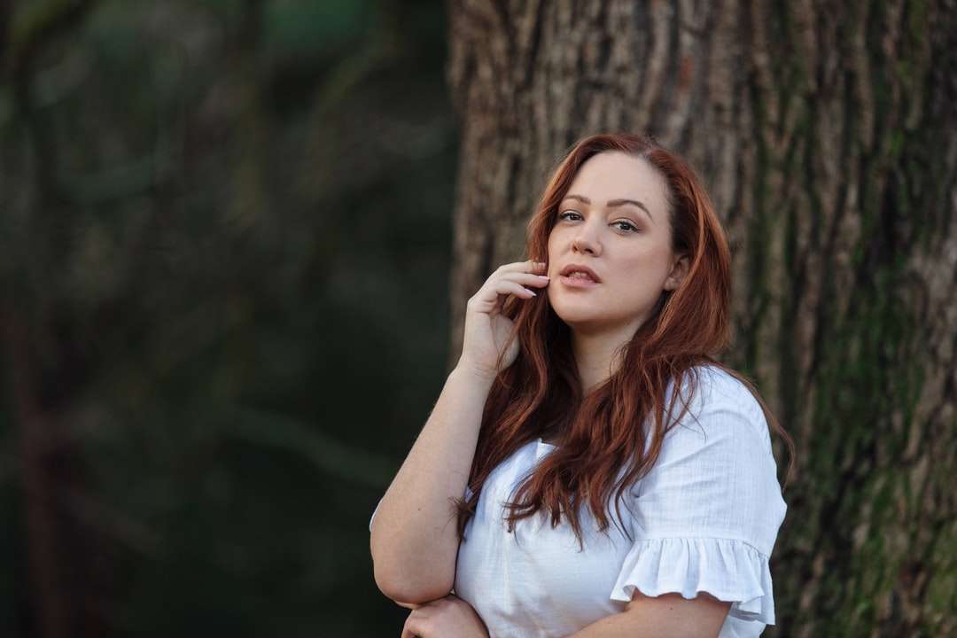 Frau im weißen Hemd, das sich auf braunen Baum stützt Online-Puzzle