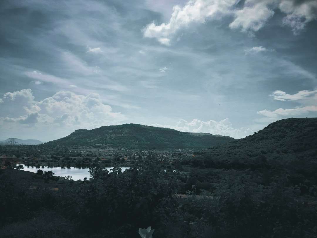 munți verzi lângă corpul de apă sub cerul albastru jigsaw puzzle online