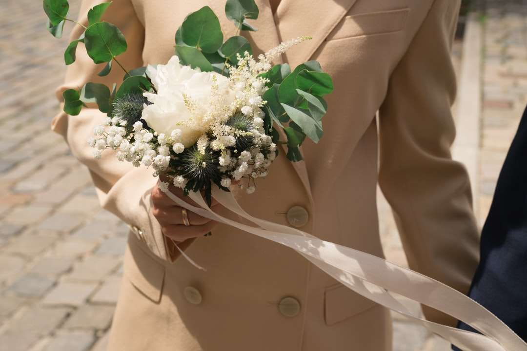 Femme en blazer beige tenant un bouquet de fleurs blanches puzzle en ligne