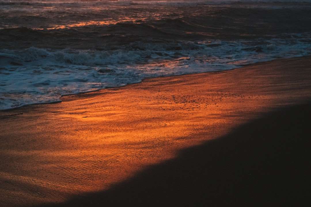 Ozeanwellen, die während des Sonnenuntergangs am Ufer abstürzen Online-Puzzle