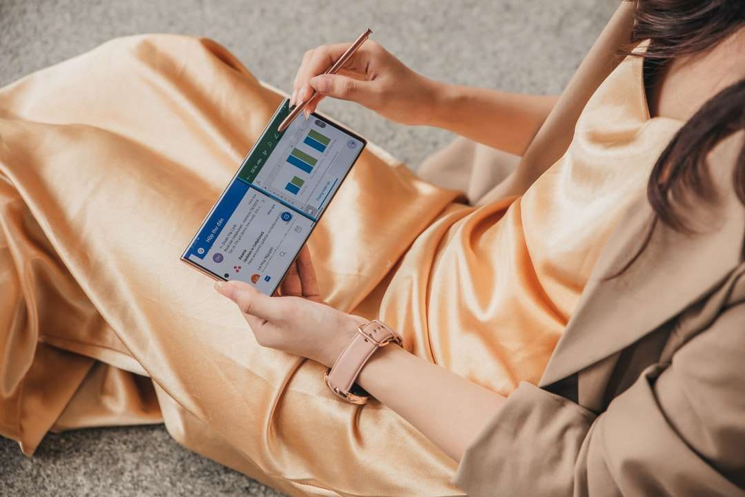 žena v béžových šatech drží modrý rámeček skládačky online