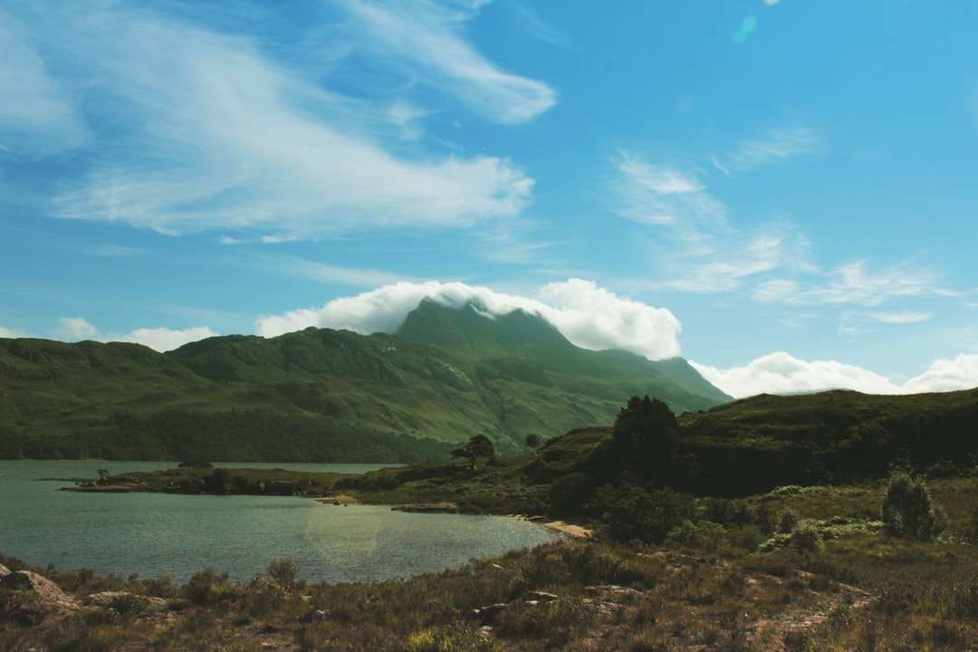 zöld hegyek közelében víztömeg kék ég alatt kirakós online