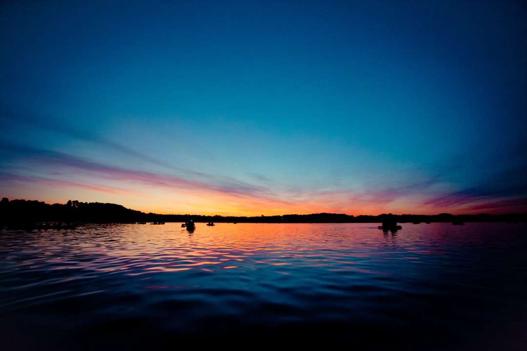 silueta de personas en el cuerpo de agua durante la puesta de sol rompecabezas en línea
