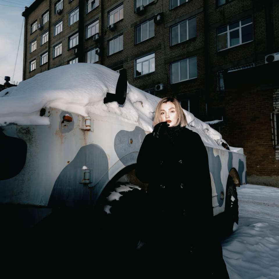 nő fekete kabátot állt a hóval borított földön online puzzle