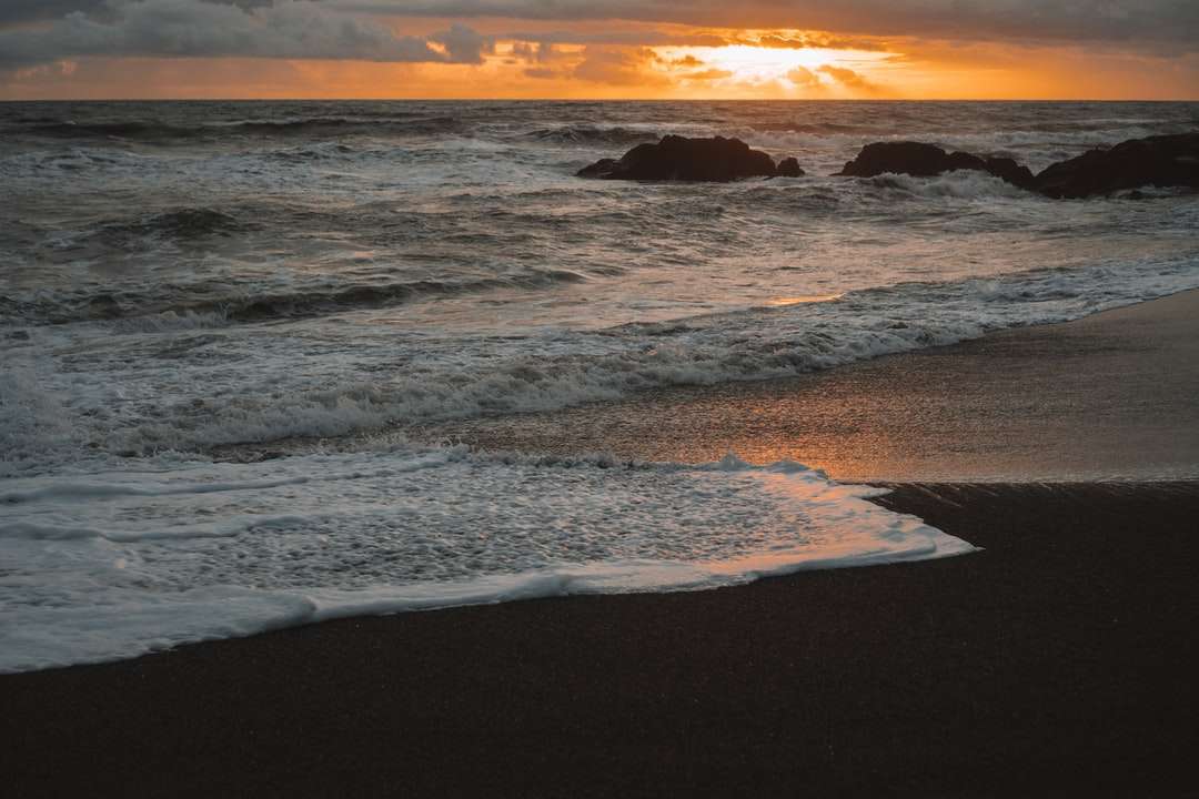 океанські хвилі розбиваються на берег під час заходу сонця пазл онлайн