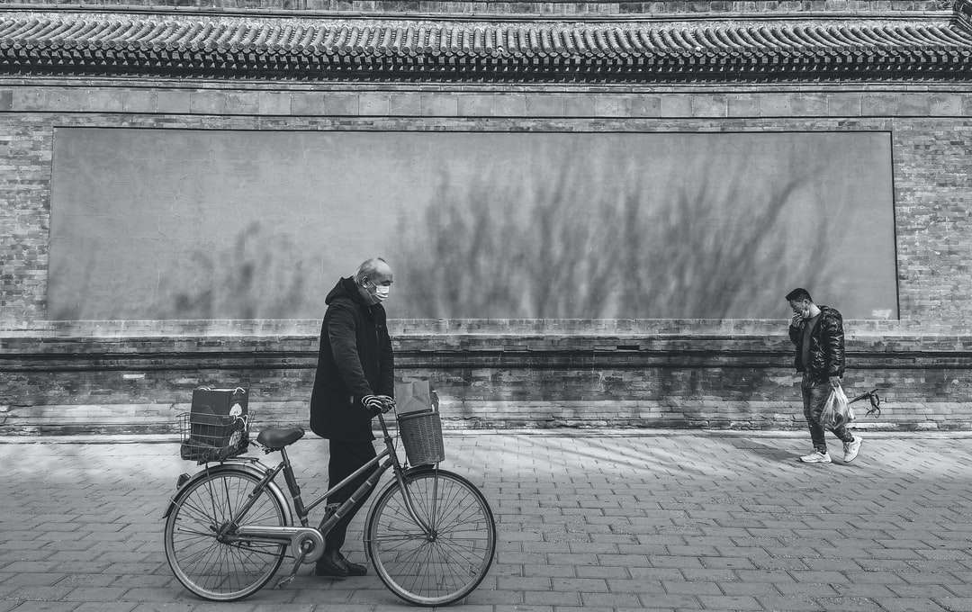 grayscale photo of woman standing beside bicycle near body online puzzle