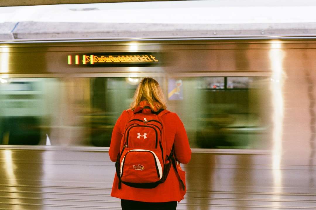 電車の前に立っている赤い長袖シャツの女性 オンラインパズル