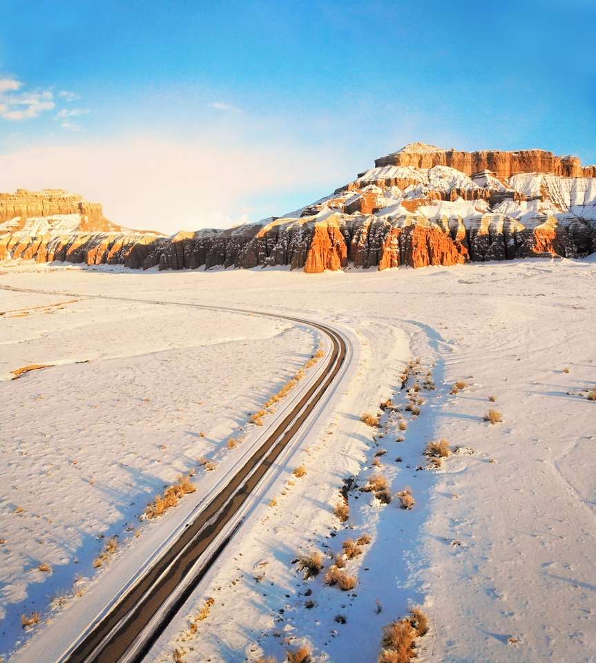 estrada coberta de neve perto da montanha marrom durante o dia puzzle online