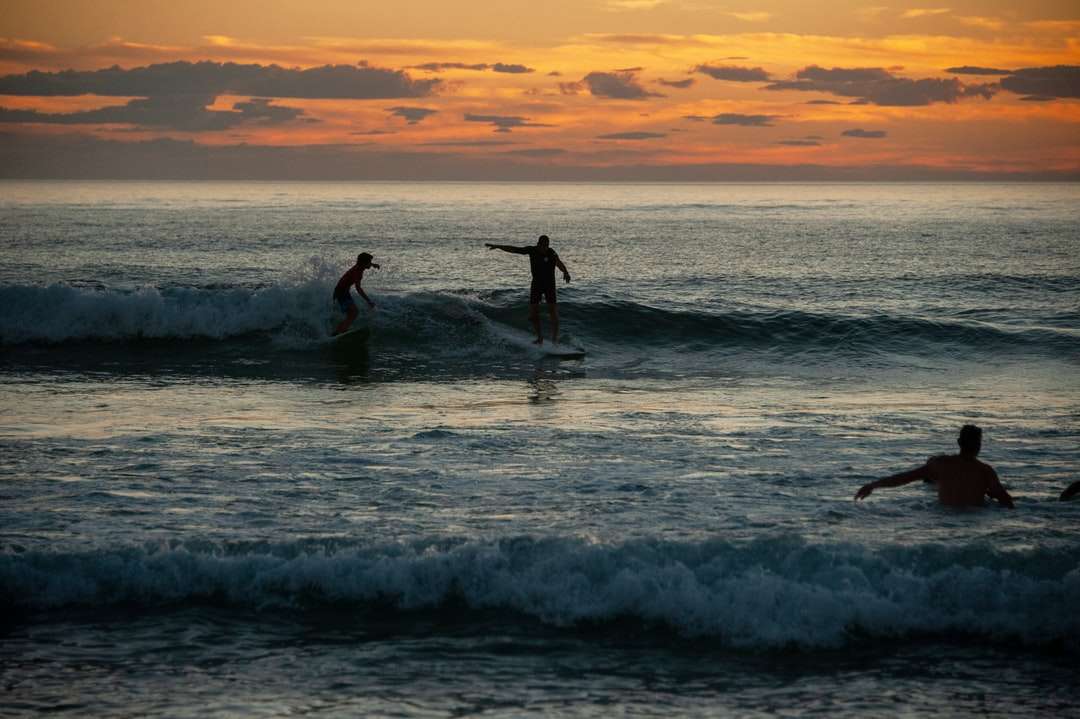 2 Personen, die während des Sonnenuntergangs auf Meereswellen surfen Online-Puzzle