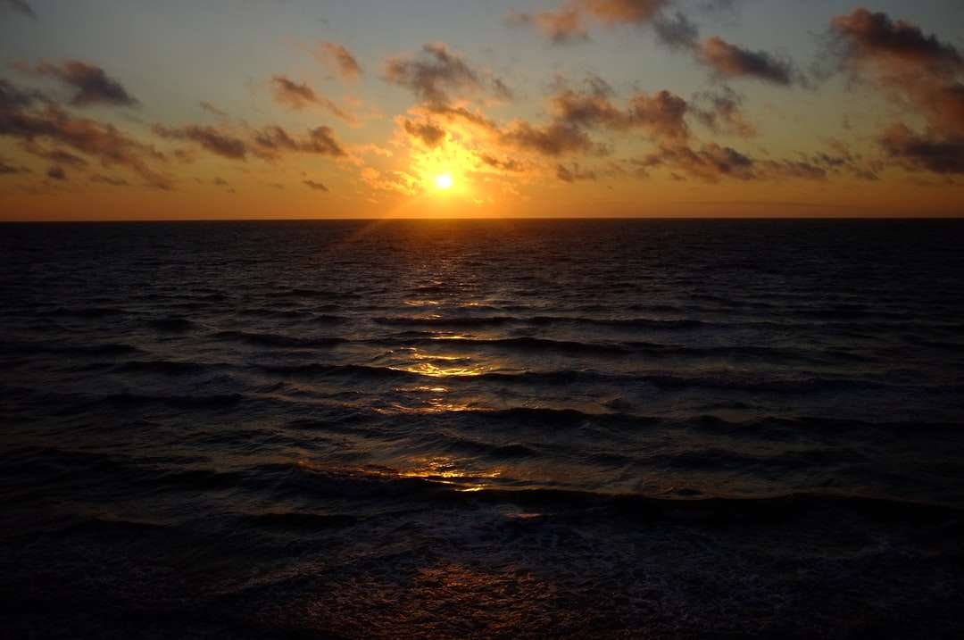 морські хвилі розбиваються на берег під час заходу сонця онлайн пазл