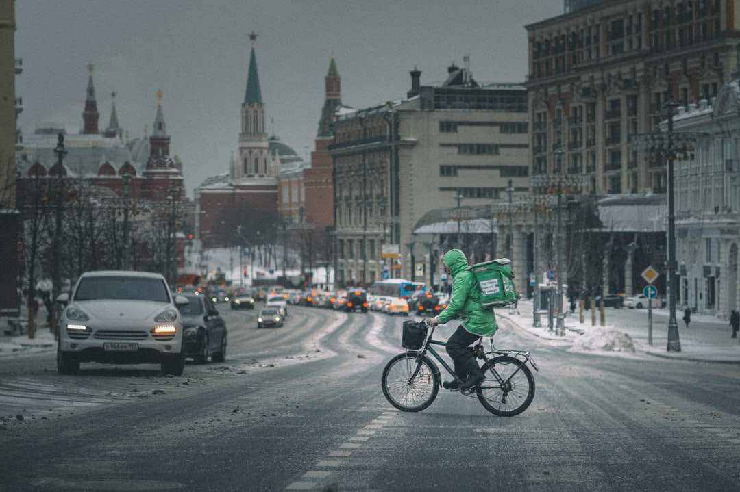 Mann in der grünen Jacke, die tagsüber Fahrrad auf Straße fährt Puzzlespiel online