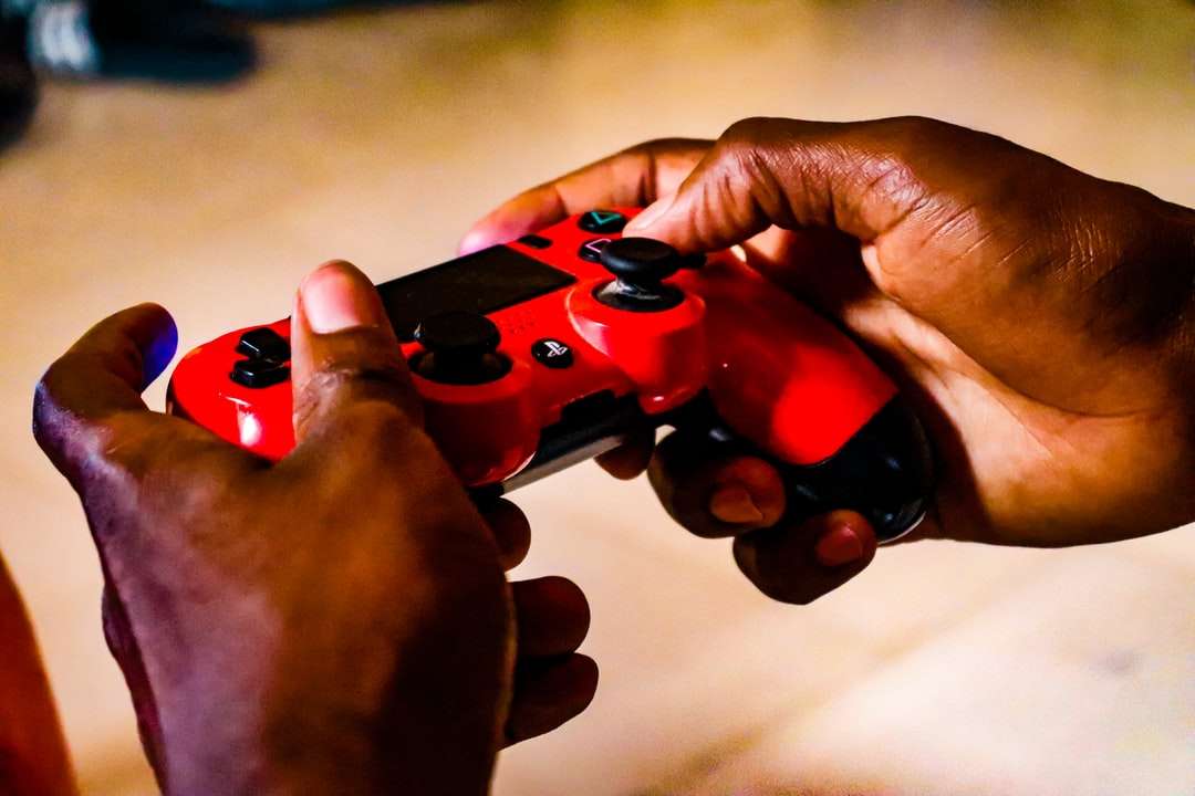 άτομο που κρατά τον κόκκινο και μαύρο ελεγκτή παιχνιδιών παζλ online