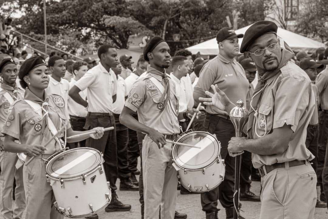 foto en escala de grises de hombres con camisa blanca y pantalones tocando el tambor rompecabezas en línea
