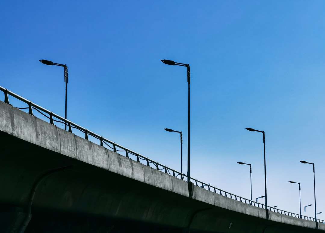 Poteau en métal noir sur pont en béton gris sous ciel bleu puzzle en ligne