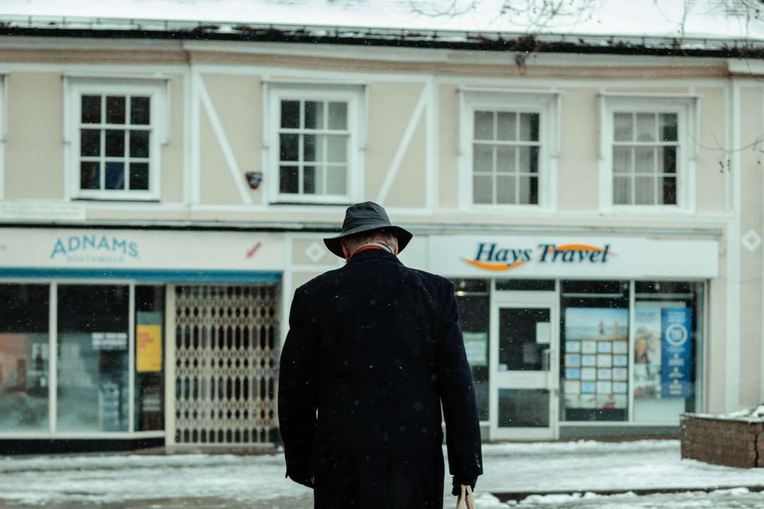 Hombre de abrigo negro caminando sobre suelo cubierto de nieve rompecabezas en línea