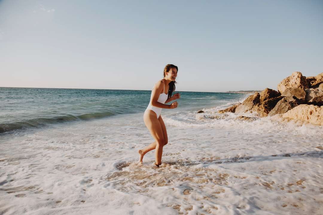 昼間にビーチに立っている白いビキニの女性 オンラインパズル