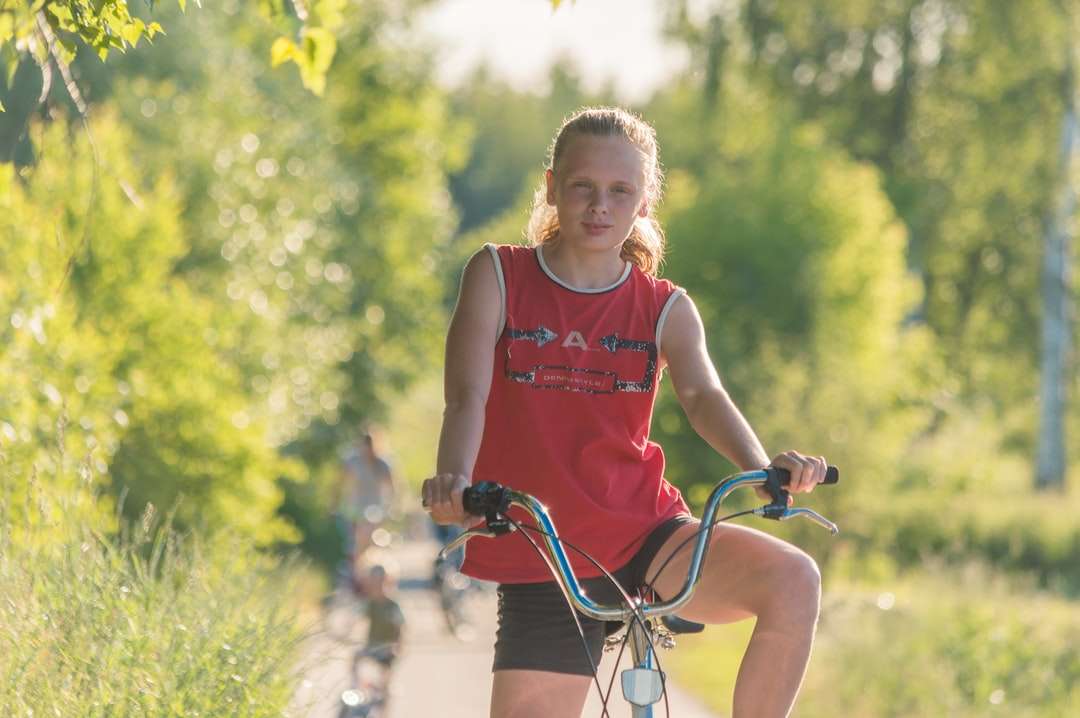 garota de camiseta vermelha andando de bicicleta durante o dia quebra-cabeças online