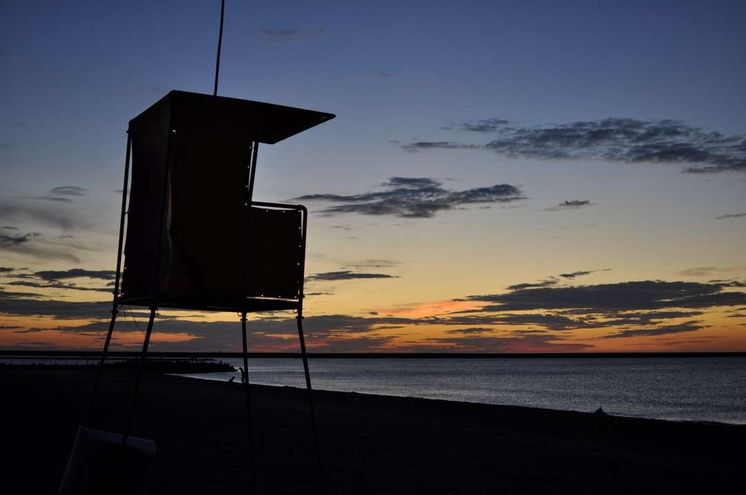 Schattenbild des Rettungsschwimmerturms am Strand während des Sonnenuntergangs Online-Puzzle