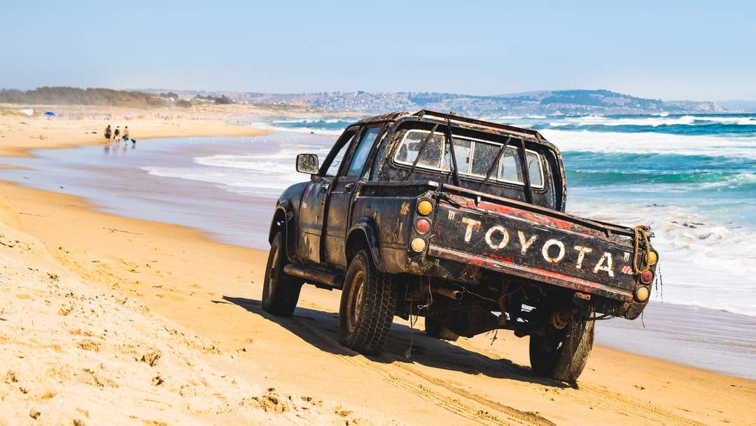 SUV negru pe nisip maro lângă corpul de apă în timpul zilei puzzle online