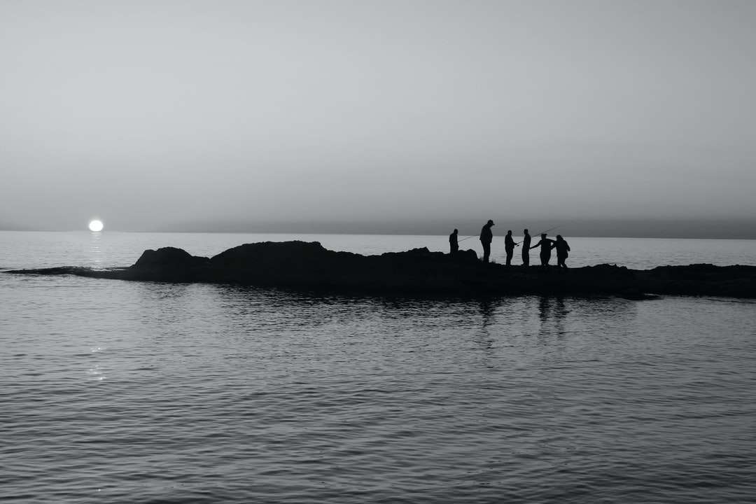 Silhouette von Menschen auf Felsformation mitten im Meer Online-Puzzle