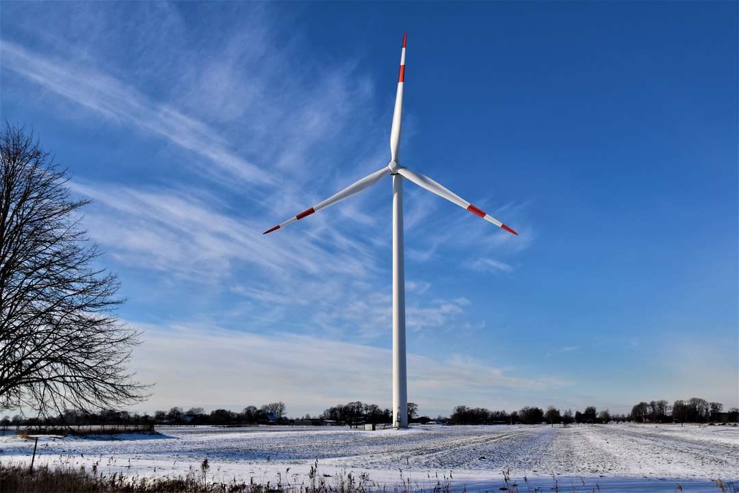 turbina eolica bianca su un terreno innevato sotto il cielo blu puzzle online