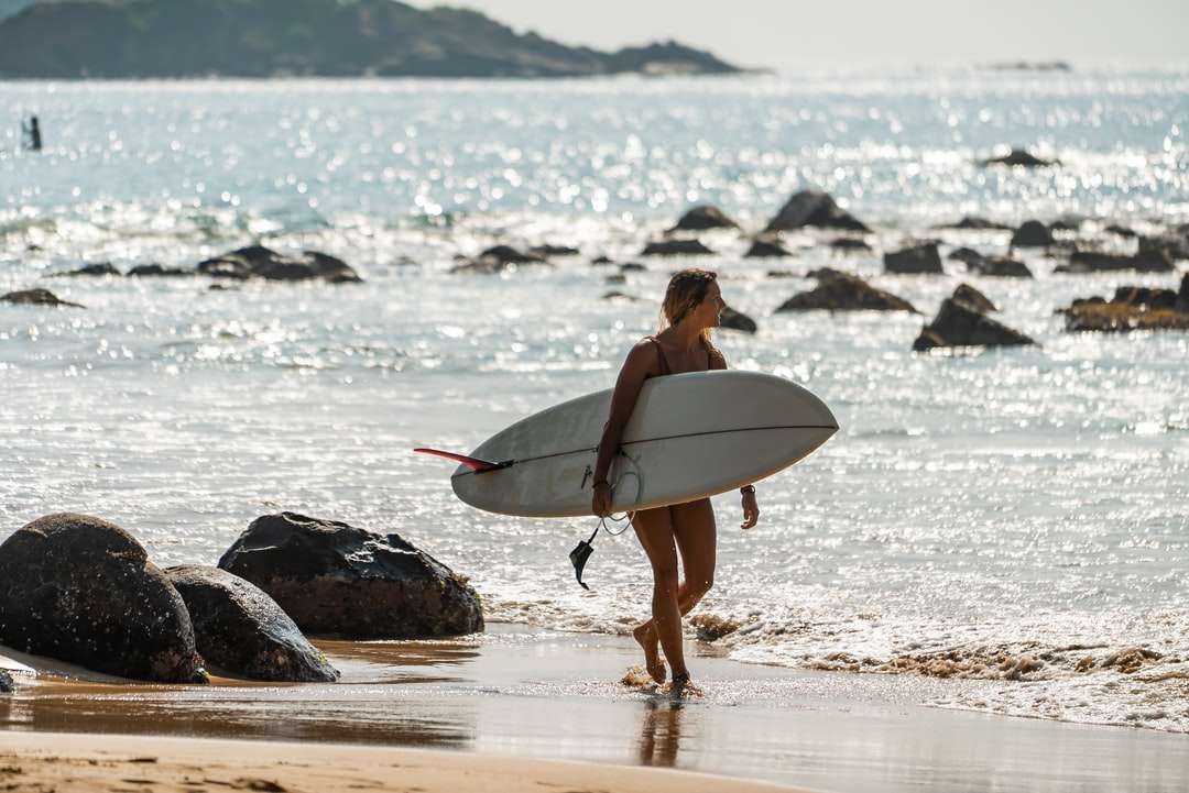 vrouw die in zwarte bikini witte surfplank houdt legpuzzel online