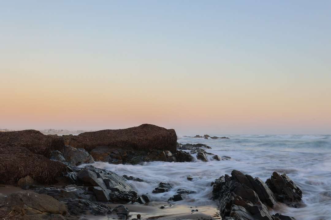Formación de roca marrón en el mar durante el día rompecabezas en línea