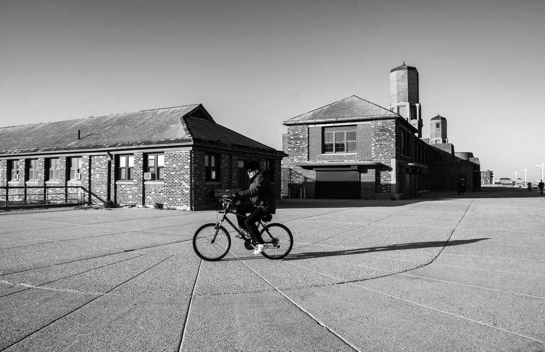 fotografie în tonuri de gri a omului călare pe bicicletă pe drum jigsaw puzzle online