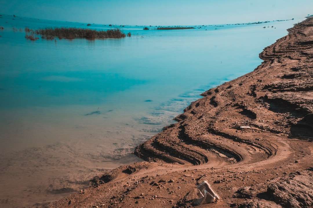 nisip maro lângă corpul de apă în timpul zilei jigsaw puzzle online