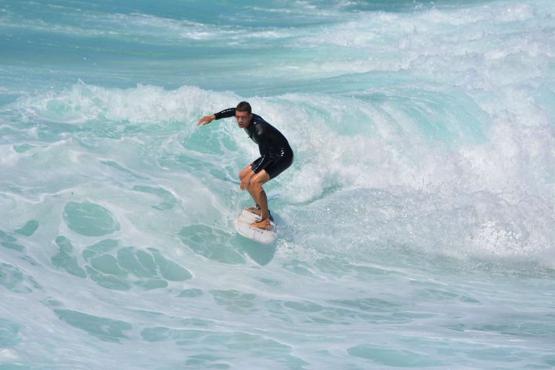 мужчина в черной рубашке и шортах занимается серфингом на морских волнах онлайн-пазл