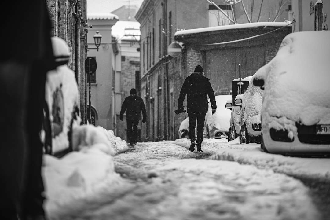 homem de jaqueta preta andando na estrada coberta de neve puzzle online