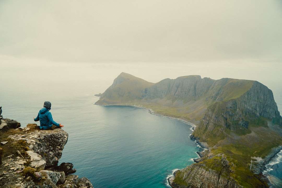 donna in giacca blu seduto sulla formazione rocciosa vicino al corpo puzzle online