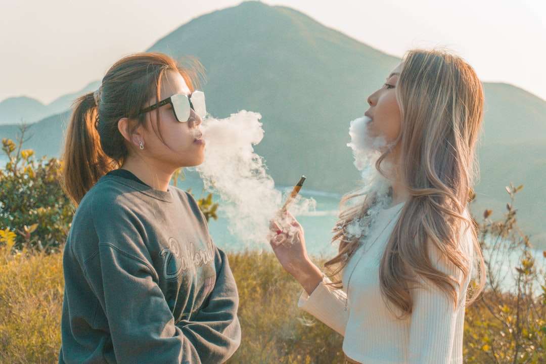 Mujer en camisa blanca de manga larga fumando junto a la mujer rompecabezas en línea