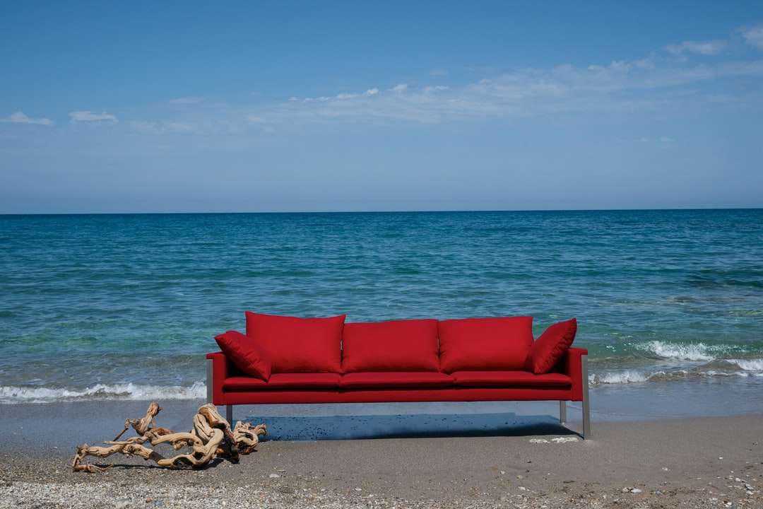 rote gepolsterte Couch am Strandufer während des Tages Online-Puzzle